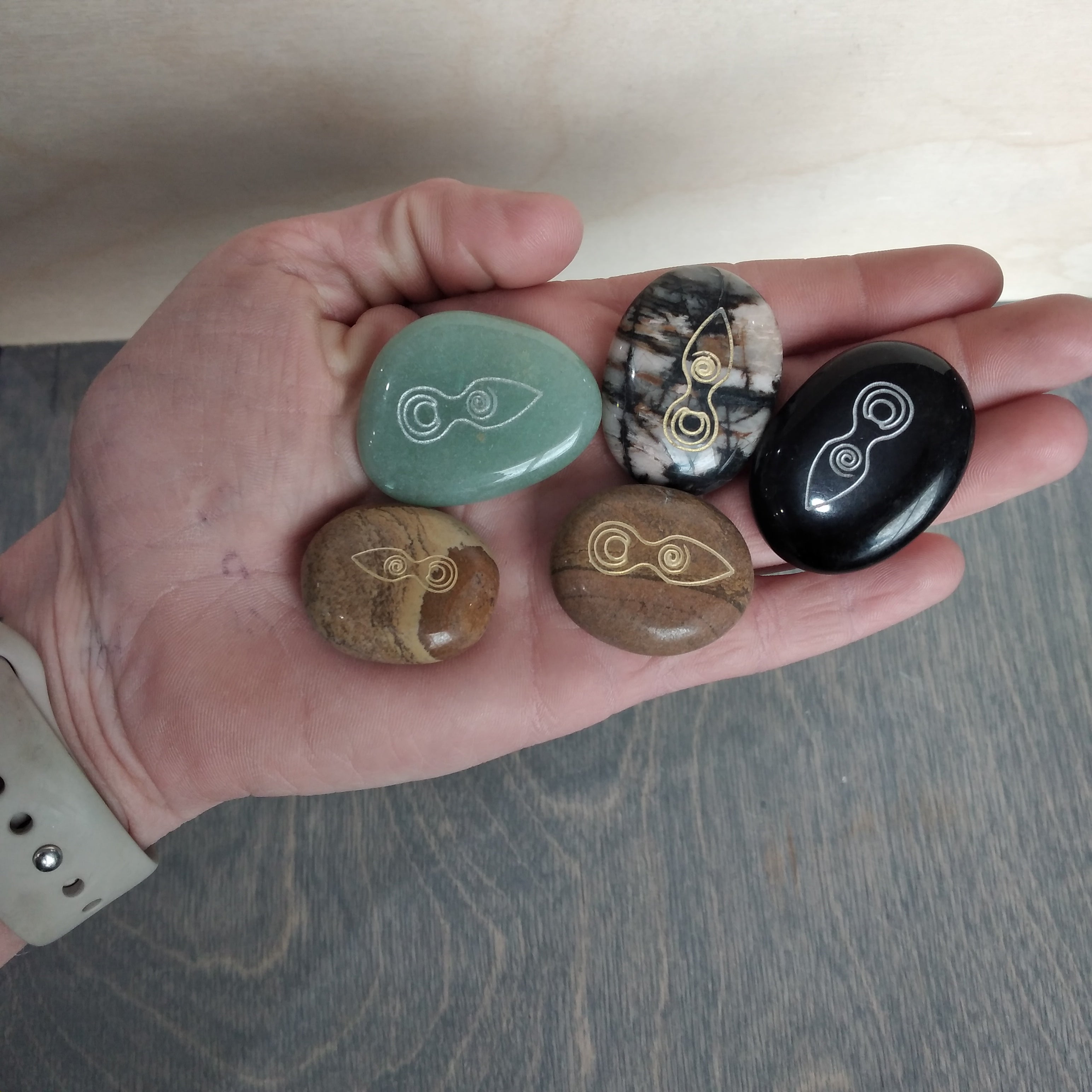 5 gemstone etched palm stones in hand.