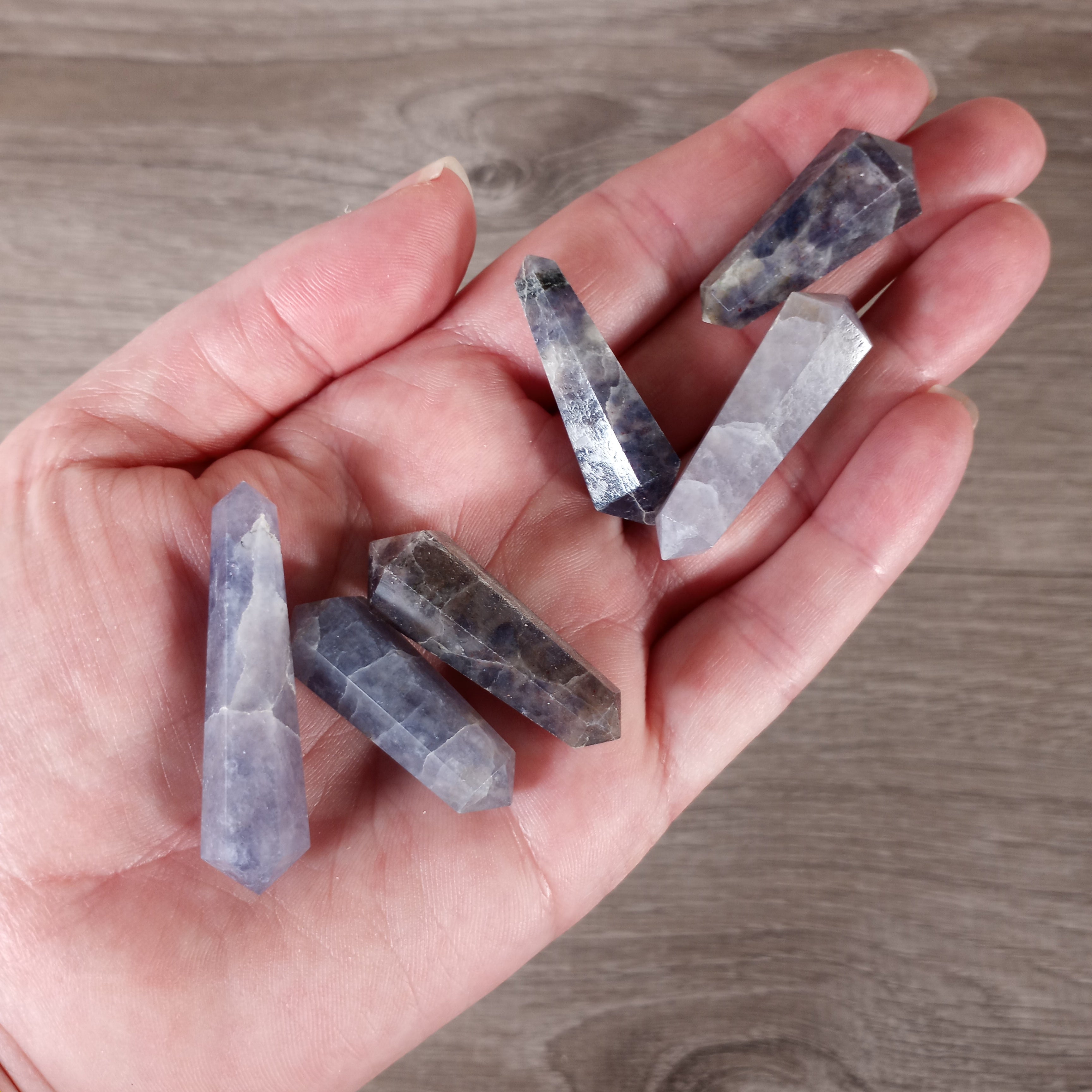 Small double terminated iolite wand on a hand with grey background - ideal for wholesale crystal retailers