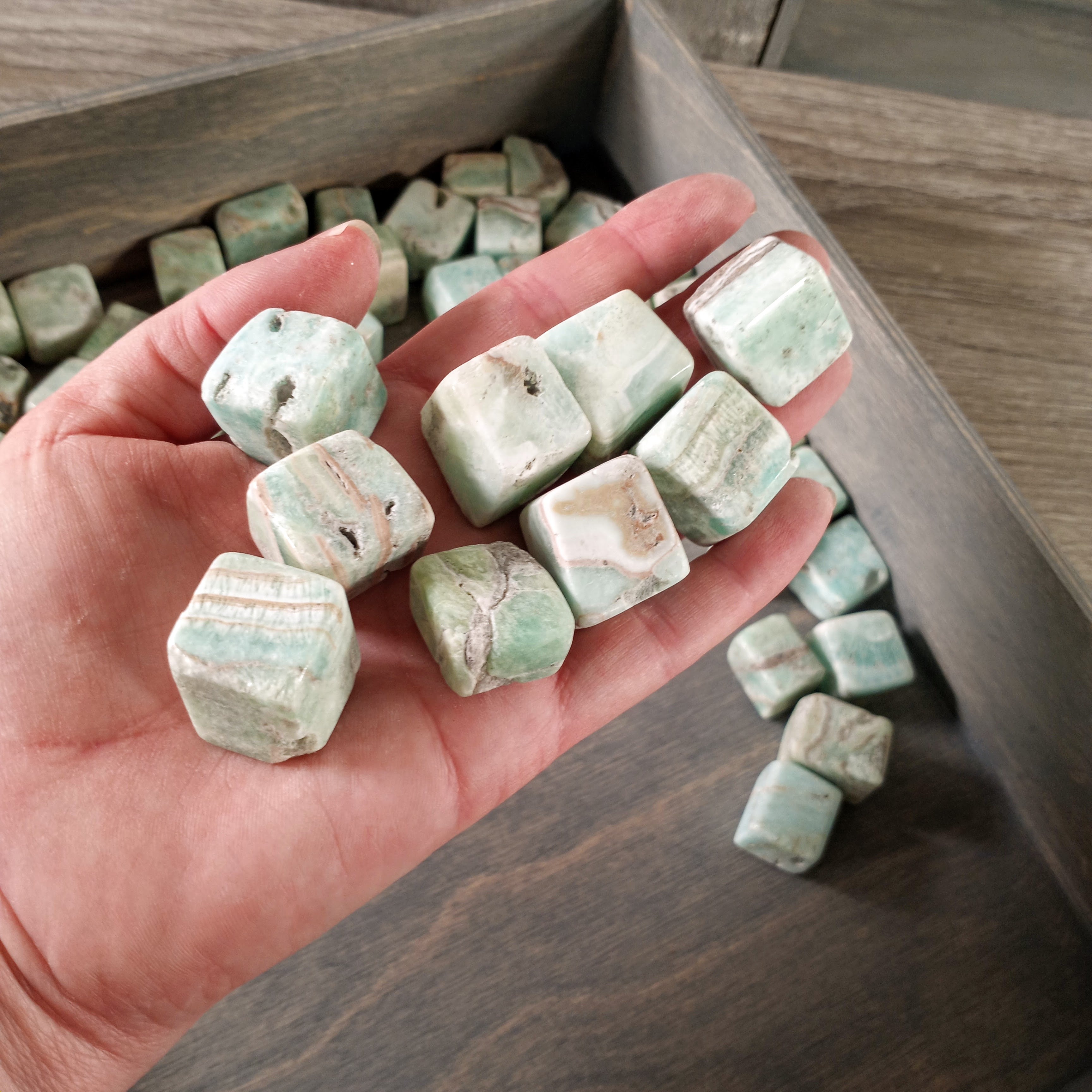 Cubic tumbled Blue Aragonite stones arranged on a grey background, ideal for wholesale buyers