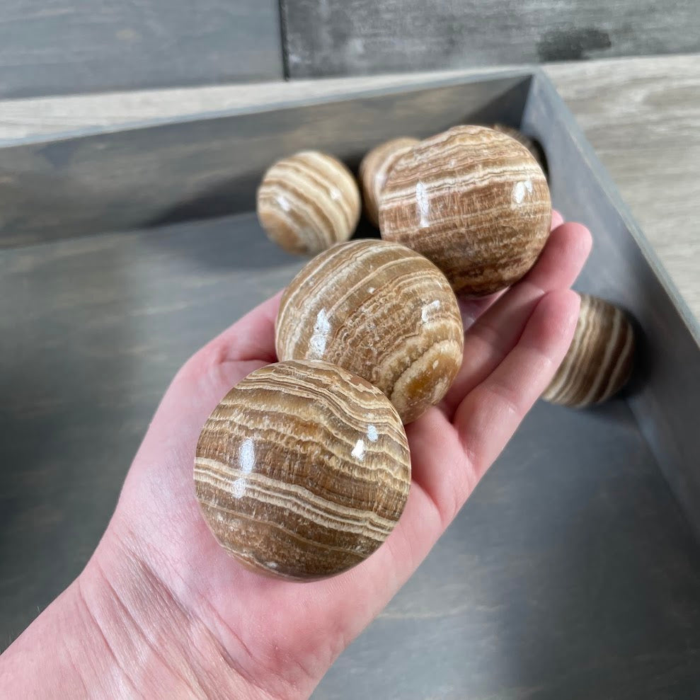 Natural Aragonite mineral sphere with warm rustic banding and smooth polish