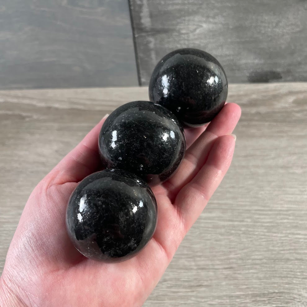 Dark polished gemstone sphere made from natural nuummite