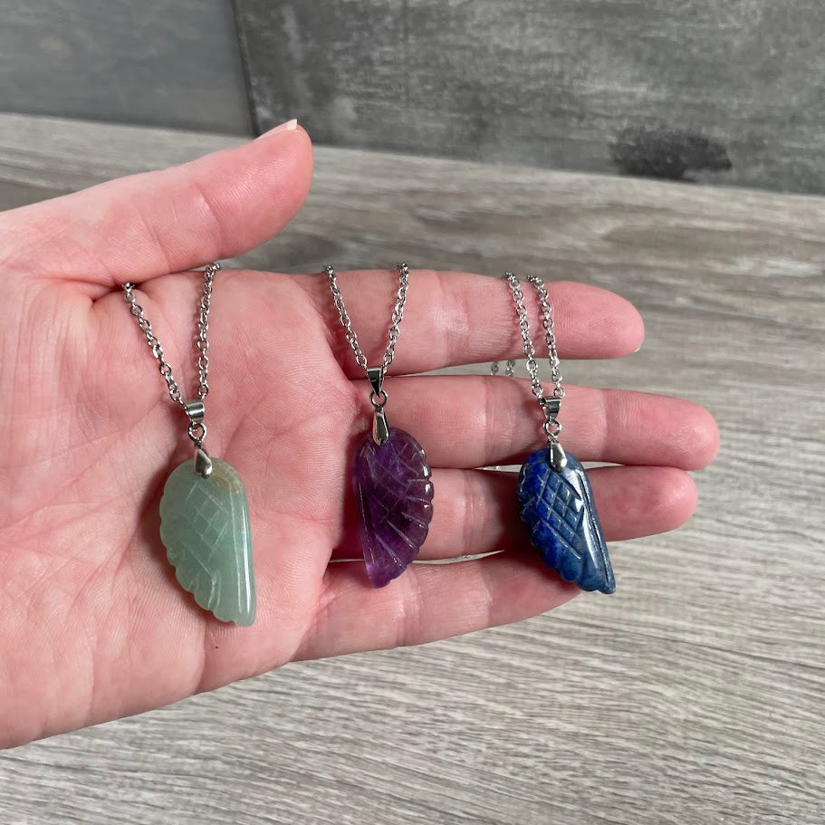 Close-up of angel wing pendant with natural crystal stones for metaphysical shops