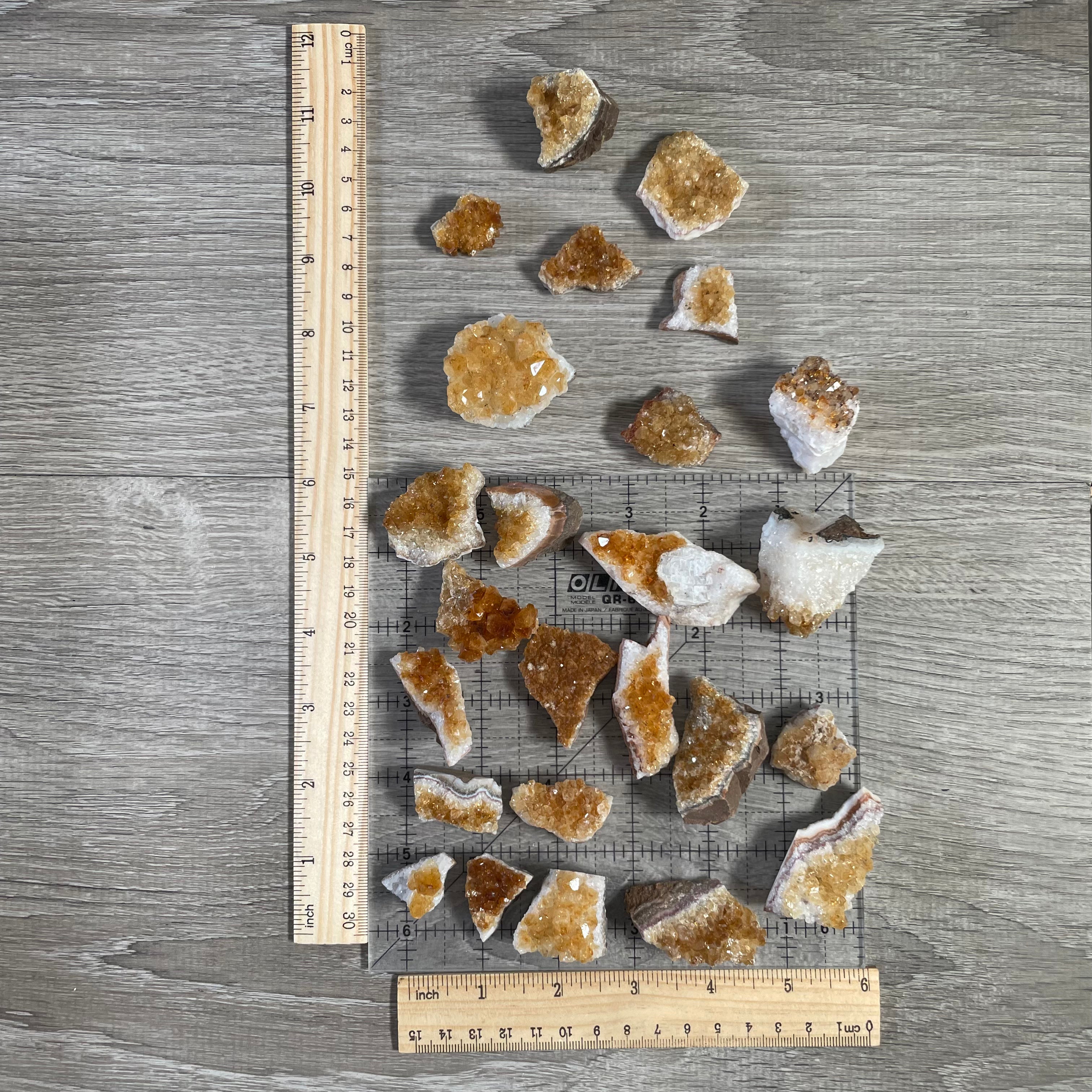 Display of multiple citrine clusters  1-pound bulk lot with a grey background and rulers with a grid.