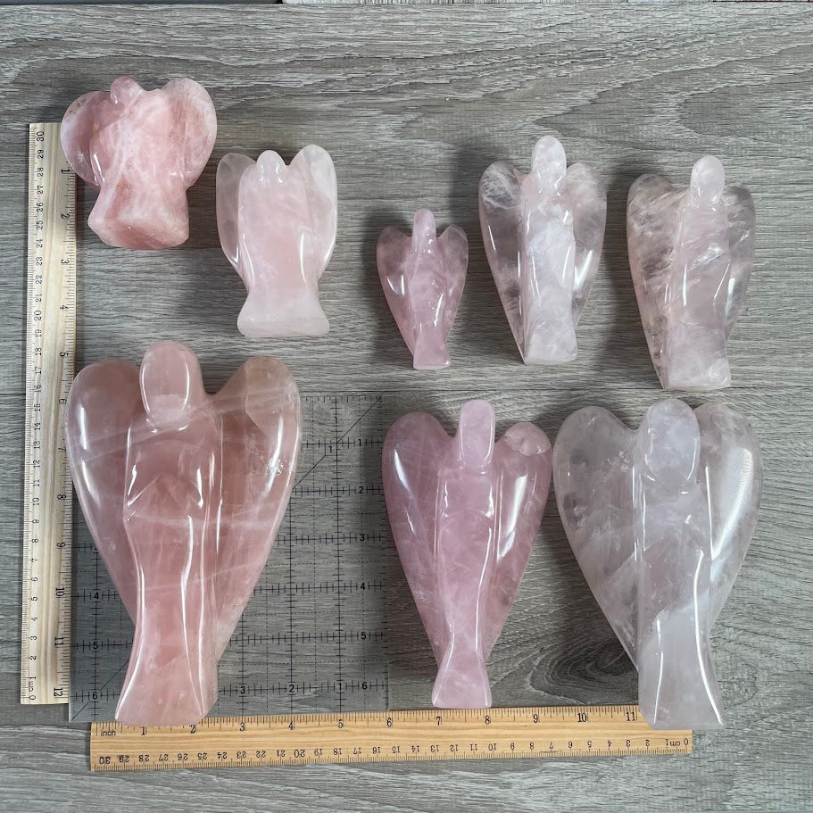 Lot of 8 rose quartz angels next to size reference. 