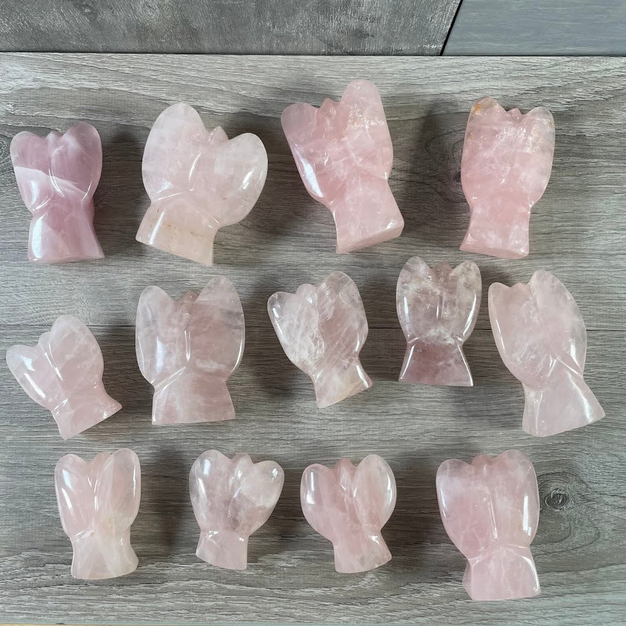 Lot of 13 stocky rose quartz angels, laying on their front, back facing up.