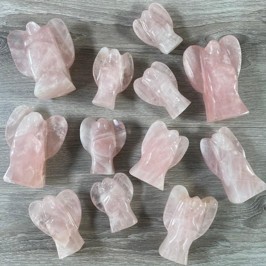 Lot of 12 stocky rose quartz angels, facing up, laying on their back.