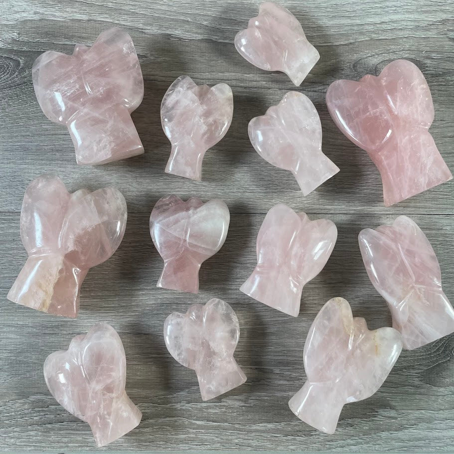 Lot of 12 stocky rose quartz angels, back facing up, laying on their front. 