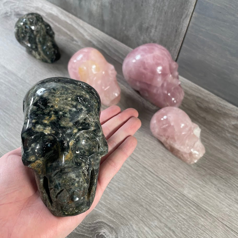 Close up of Kambaba jasper skull with rose quartz and Kambaba jasper skull in the background. 