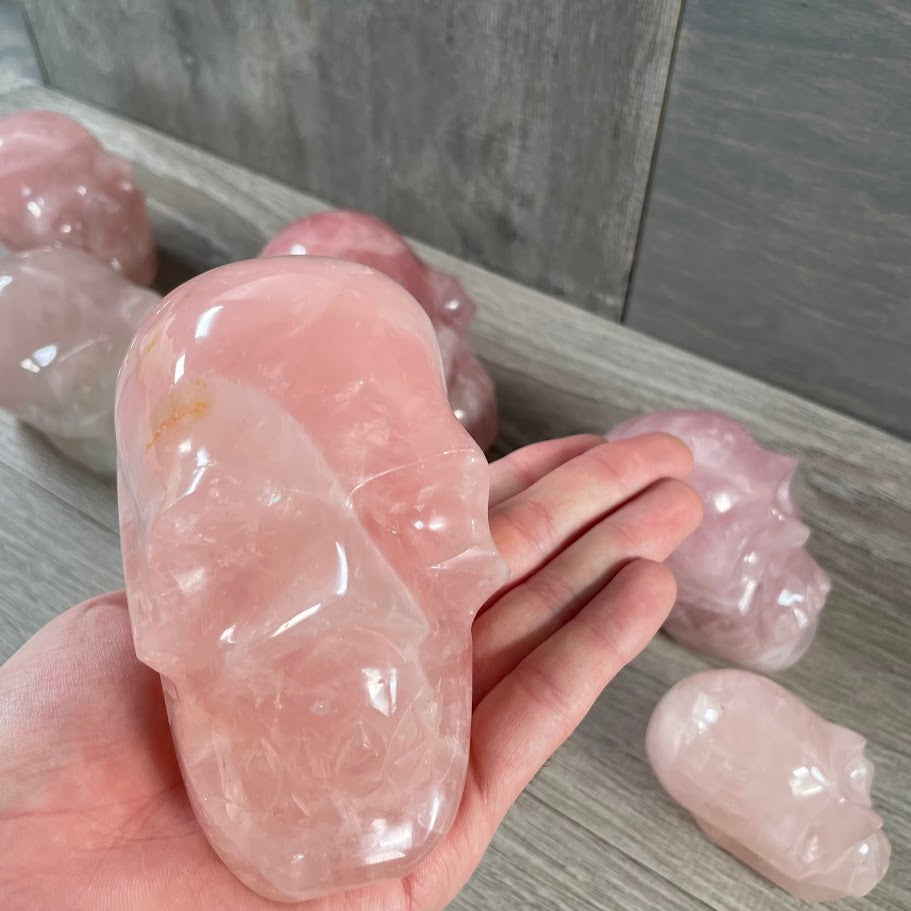Close up of rose quartz skull with other rose quartz skulls in the background. 