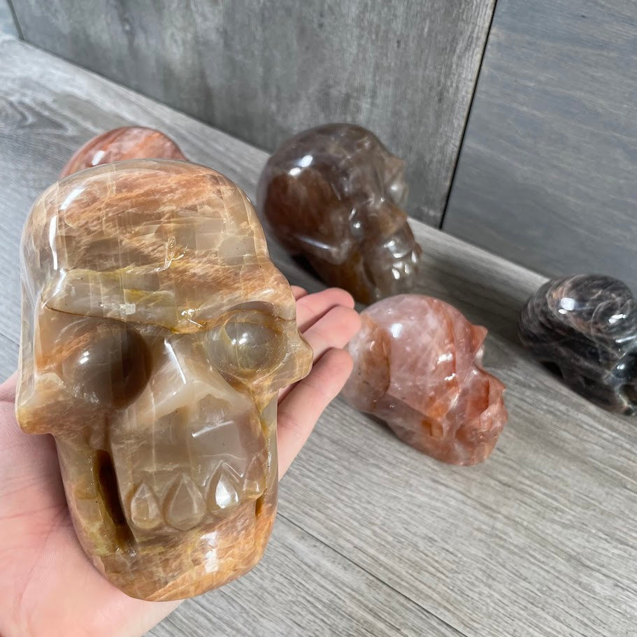 Close up of peach moonstone skull with other skulls in the background. 