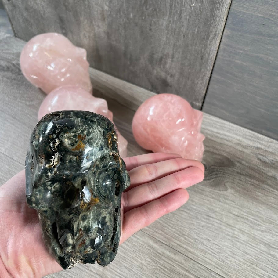 Close up of Kambaba jasper skull with rose quartz skulls in the background. 