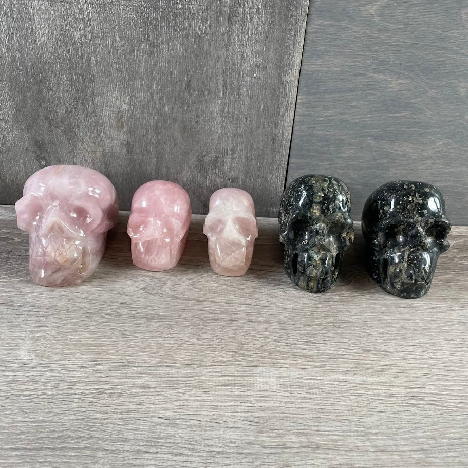 Lot of three rose quartz and two Kambaba jasper skulls; facing forwards.