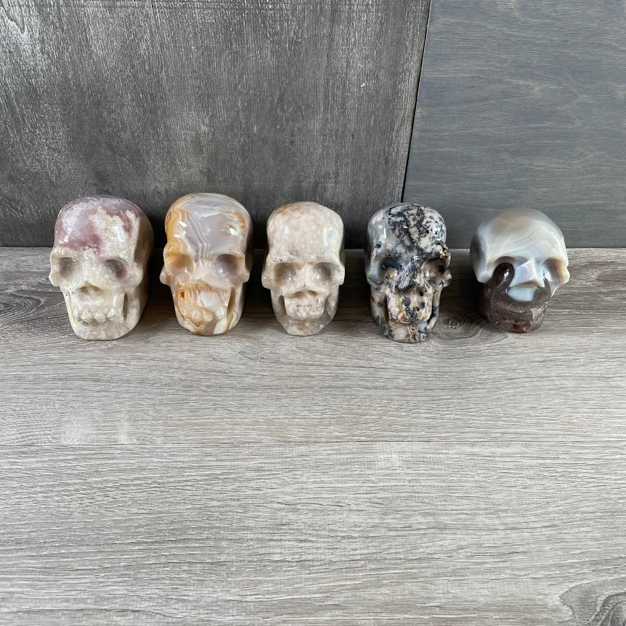 Lot of three quartz and two agate skulls; facing forwards.