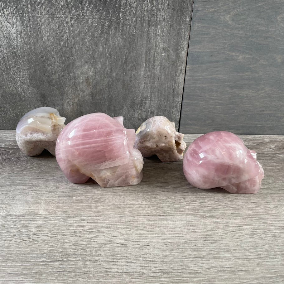 Lot of two rose quartz and two quartz skulls; facing sideways.