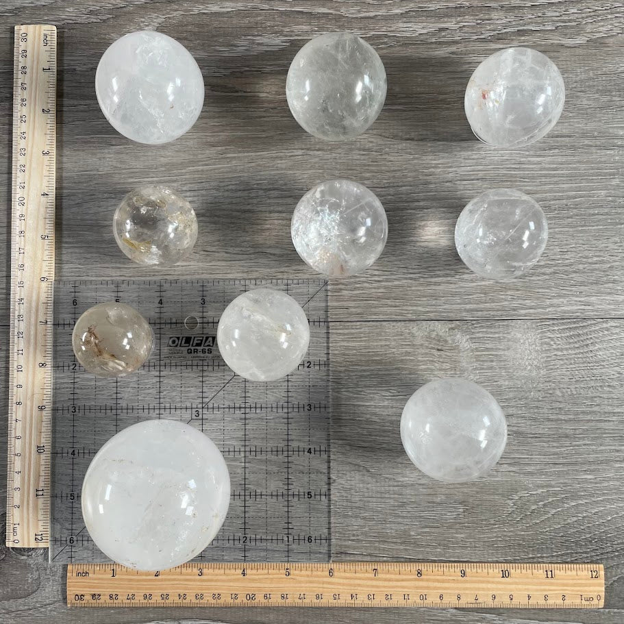 Lot of ten quartz spheres with grid and rulers for size reference. 