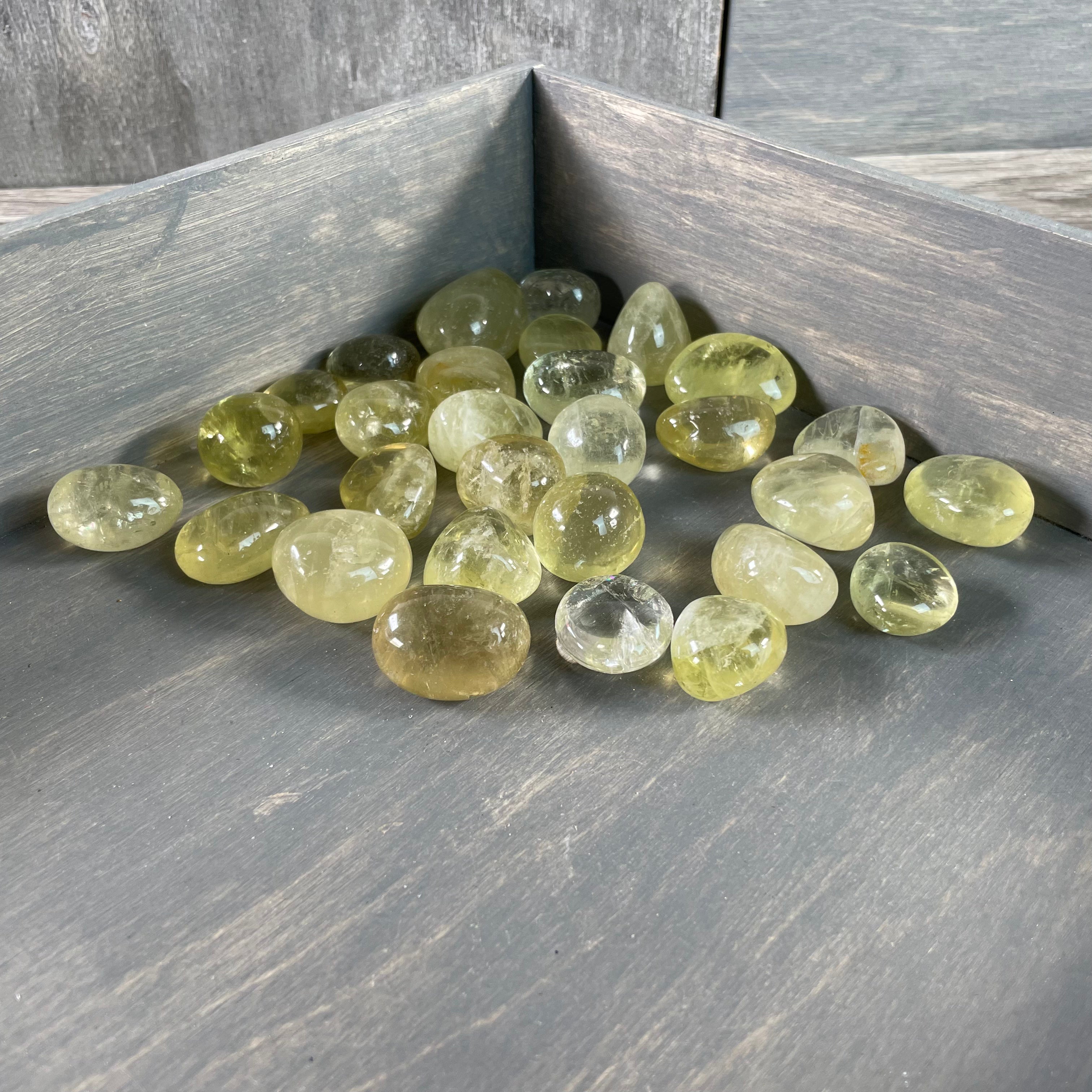 Pile of Lemon Citrine tumbled stones showcasing vibrant yellow hues, available wholesale by the pound.