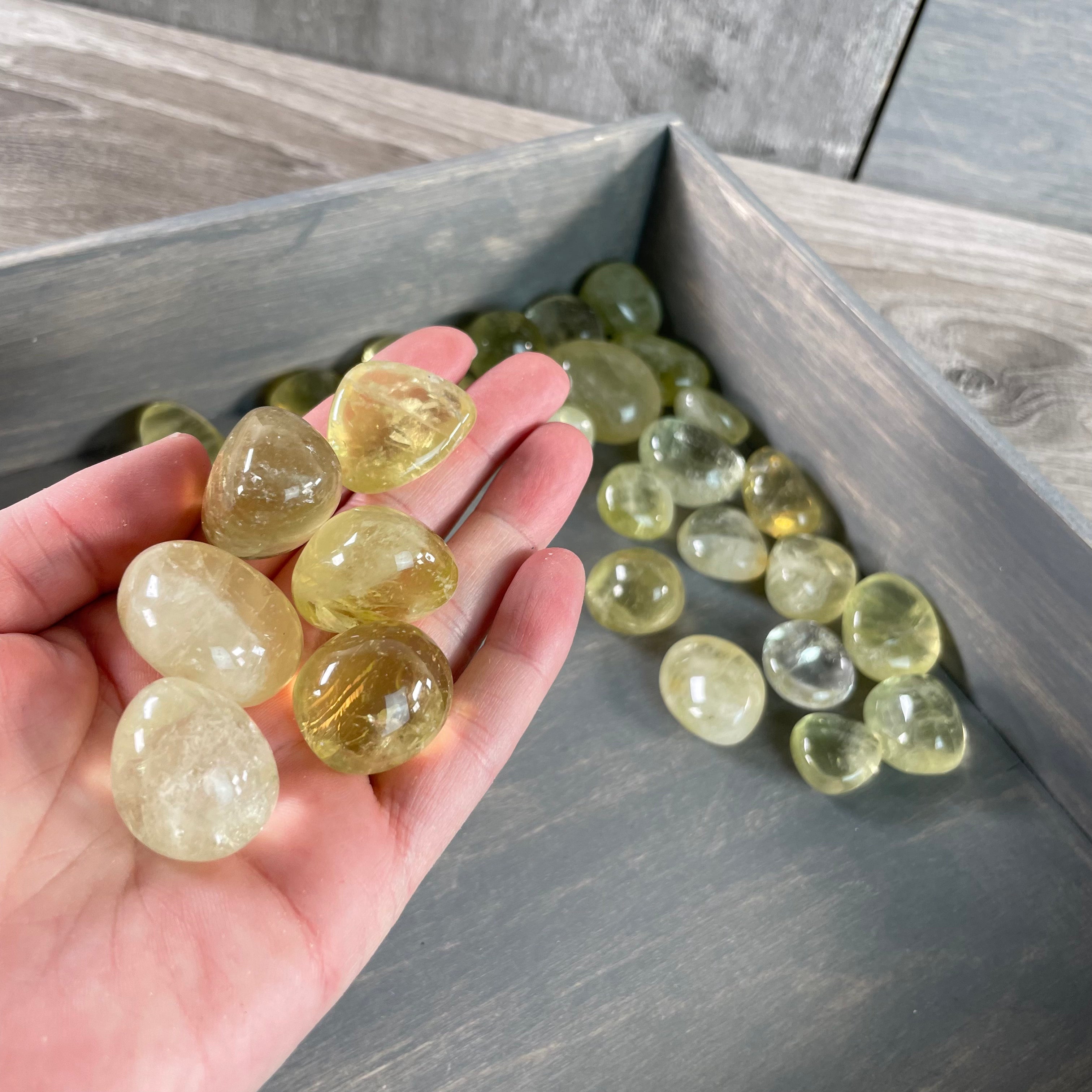 Smooth and polished Lemon Citrine tumbled stones arranged on a grey background for bulk resale.