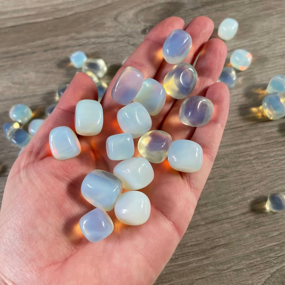 Close up of smooth opalite tumbled stones with milky white glow and iridescent finish
