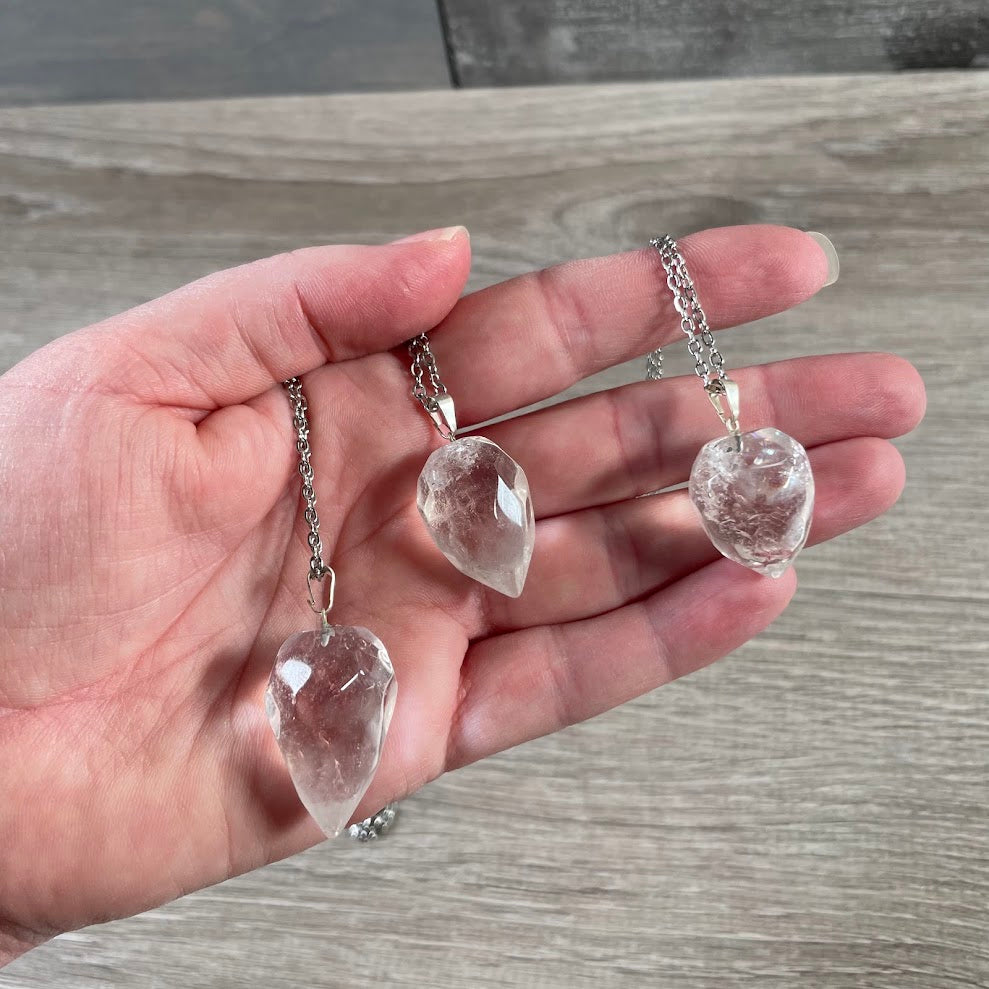 Close-up of clear quartz faceted flame gemstone pendant showing polished crystal surfaces