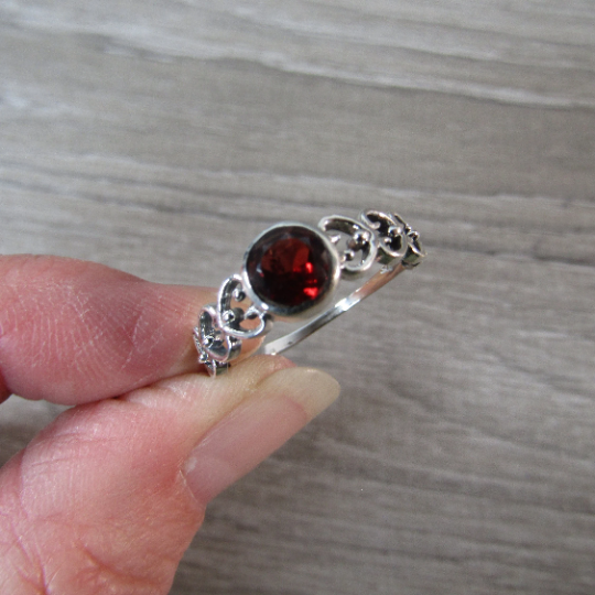 Sterling Silver ring with the band made connected hearts with a round garnet center stone