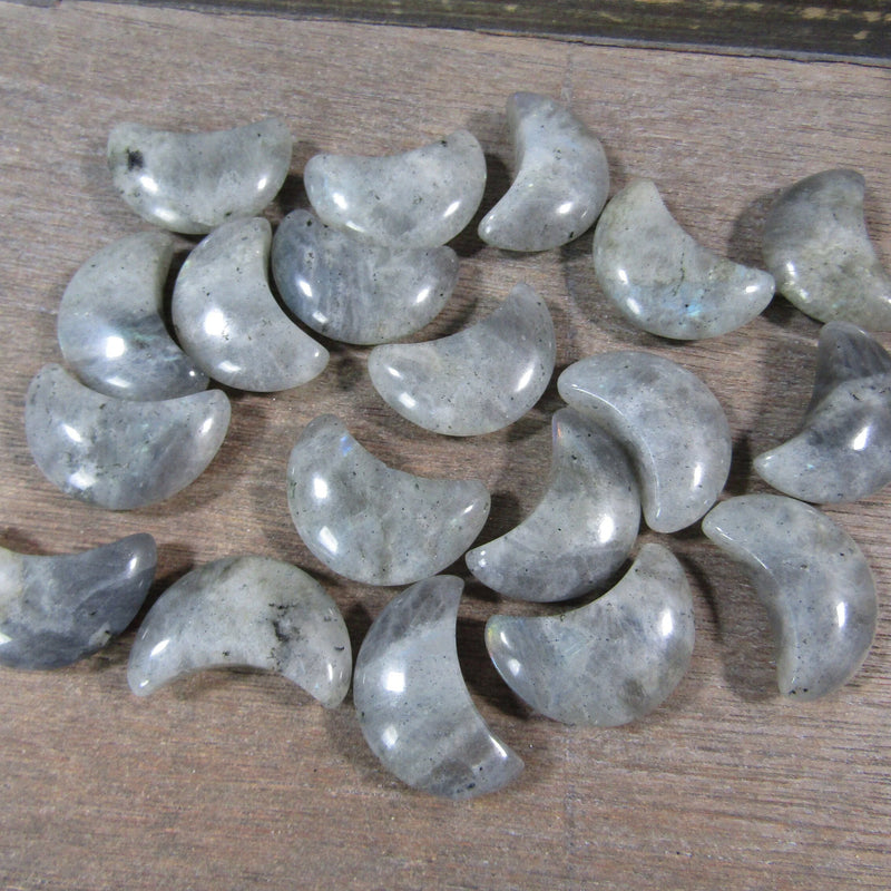 Labradorite crescent moon for sale on a hand with a grey background - Keystone Crystals