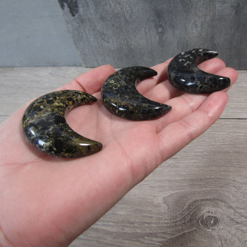  Crescent-shaped Jasper crystal moon displayed on a hand with a grey background - Keystone Crystals