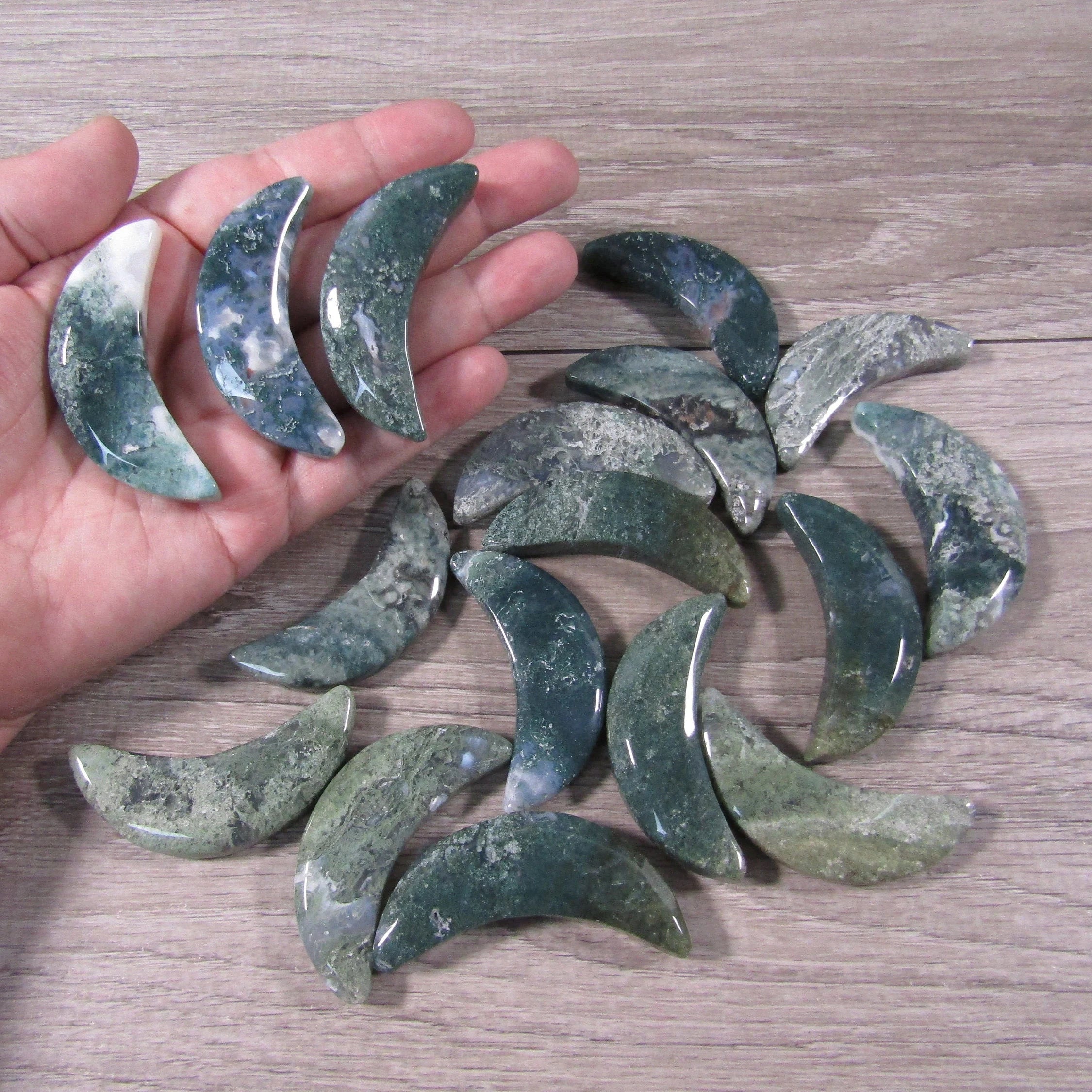 Moss Agate crescent moon crystal 2.25 inches displayed on hand grey background - Keystone Crystals