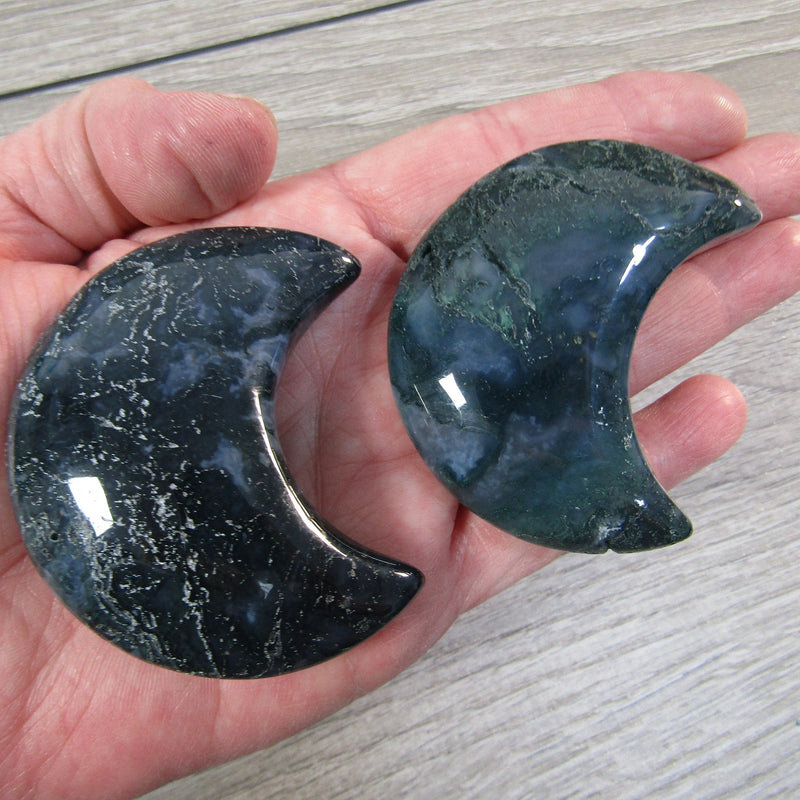 Medium-sized Moss Agate crescent moon in hand with grey background - Keystone Crystals wholesale