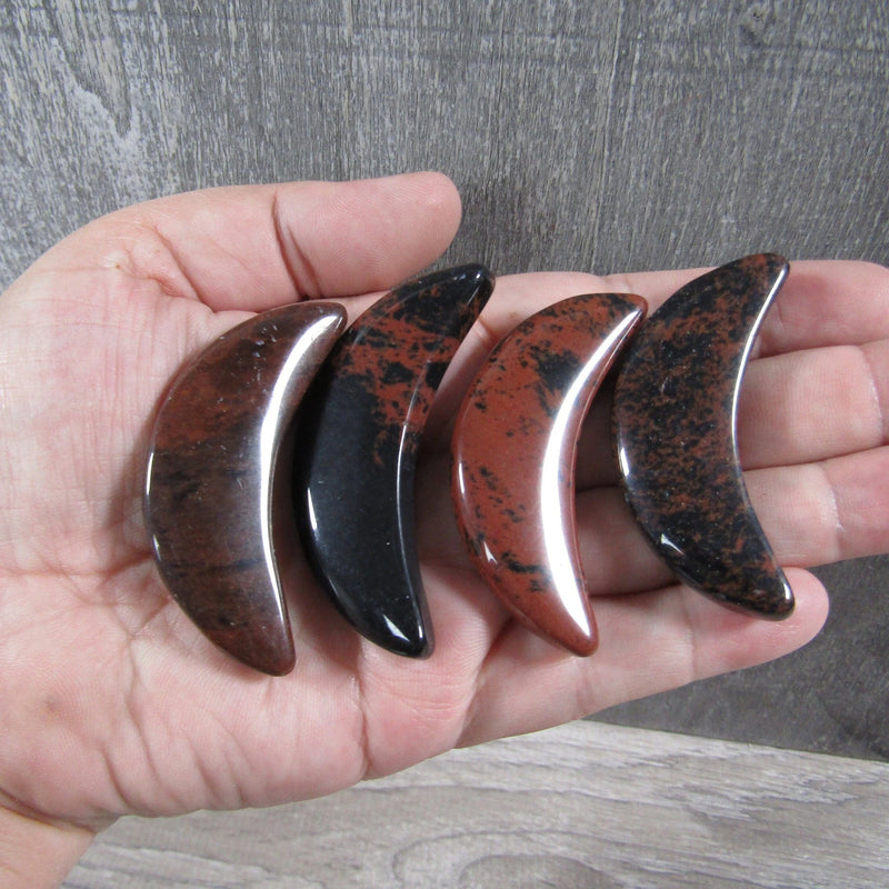 Mahogany Obsidian crescent moon stone 2.25 inches in hand grey background - Keystone Crystals