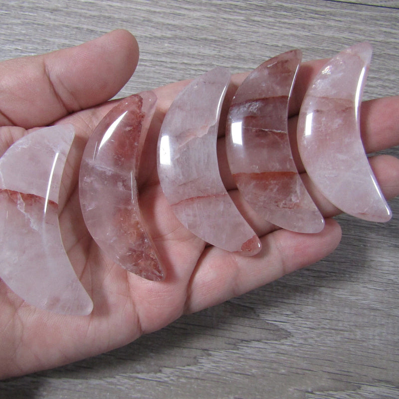 Rose Hematoid Quartz crescent moon crystal 2.25 inches held by hand grey background - Keystone Crystals