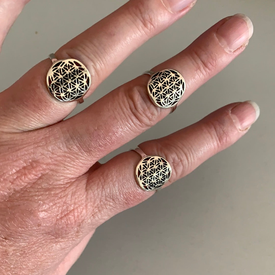 Persons hand wearing a sterling silver Flower of Life ring, highlighting its craftsmanship