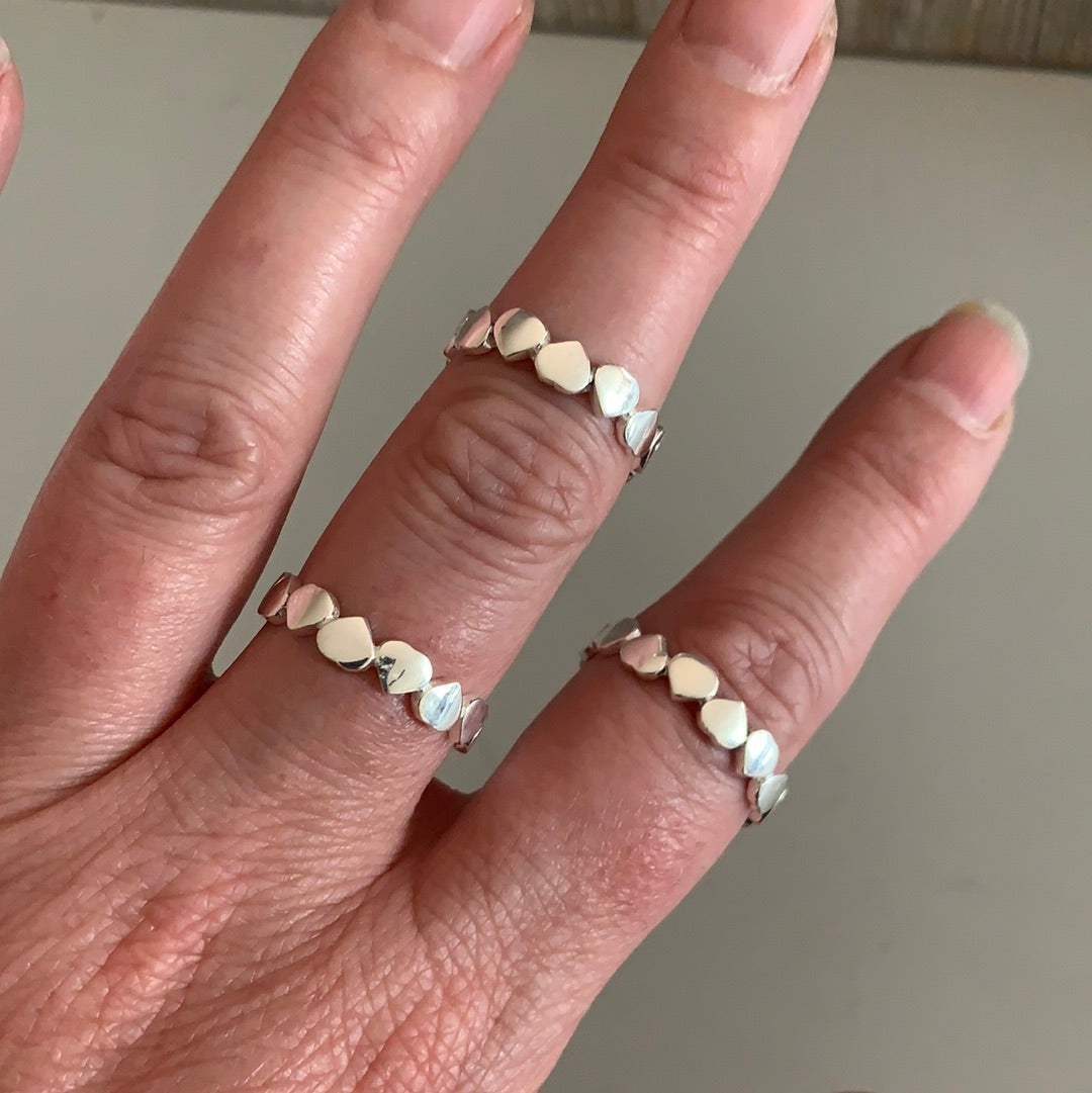 Woman's hand wearing a sterling silver heart rings, capturing the polished shine.